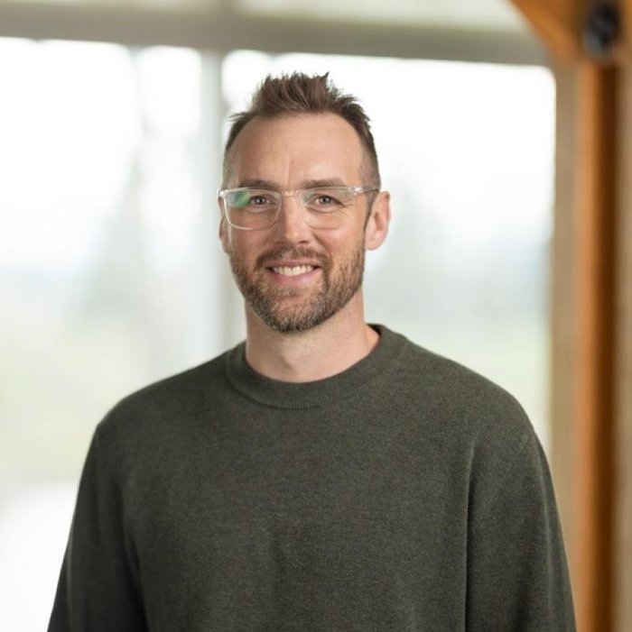 Headshot of an IGV Housing team member in a grey sweater and glasses